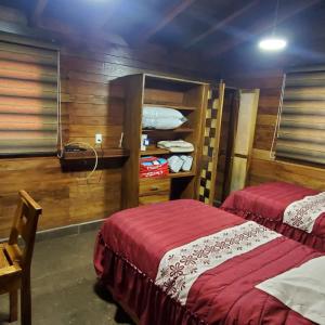 zwei Betten in einem Zimmer mit Holzwänden in der Unterkunft Cabañas Corazón in Troncones