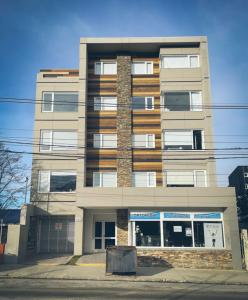 Un edificio de apartamentos alto con un bote de basura enfrente. en Departamento Austral II, en Ushuaia