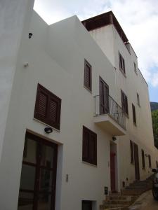 a white building with brown shuttered windows and stairs at Il Cortile Di Eolo in Marettimo