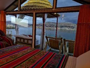 Uros Qhota Uta Lodge في بونو: غرفة نوم مع طاولة وإطلالة على الماء