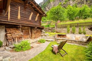 un patio con una silla frente a una casa en Appartamento Casa Weisstor con patio, giardino e orti vista Monte Rosa, en Macugnaga