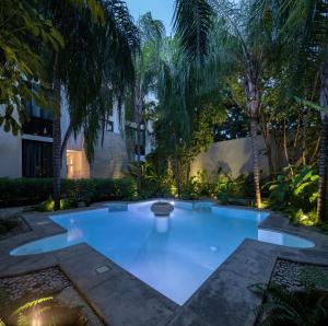 ein großer Swimmingpool mit Palmen im Garten in der Unterkunft Künük Hotel Boutique in Mérida