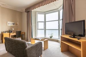 a living room with a television and a large window at Imperial Hotel Tenby in Tenby