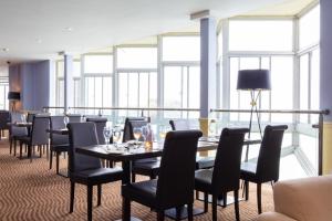 a dining room with tables and chairs and windows at Imperial Hotel Tenby in Tenby