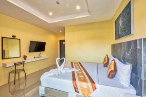 パトンビーチにあるTJ Patong Hotel - SHA Plusのベッドとテレビ付きのホテルルーム