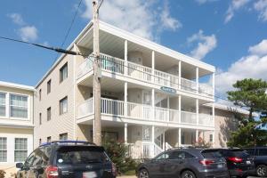 Un edificio blanco con coches aparcados delante. en Surfs Up 301, en Ocean City
