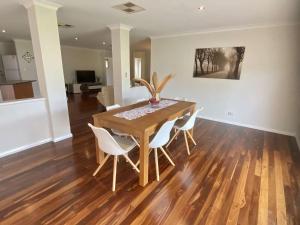 uma sala de jantar com uma mesa de madeira e cadeiras brancas em Wagon Holiday Home em Broadwater