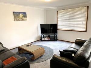 a living room with leather furniture and a flat screen tv at Gale Street Retreat Busselton in Busselton