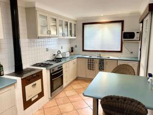 a kitchen with white cabinets and a table with chairs at Gale Street Retreat Busselton in Busselton