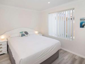 a white bedroom with a bed and a window at Studio 66 Busselton in Busselton