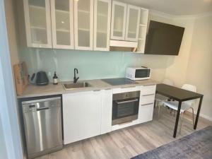a kitchen with white cabinets and a table with a microwave at Studio 66 Busselton in Busselton