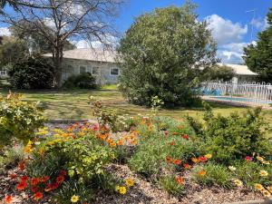 un jardin fleuri devant une maison dans l'établissement Byer Fountain Motor Inn, à Holbrook