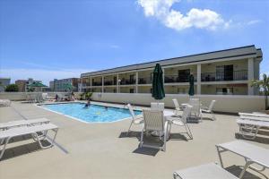 a patio with chairs and a pool and a building at Outrigger 114 in Ocean City