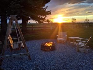 a fire pit with chairs and a table and the sunset at Gallatin Gateway Getaway in Bozeman