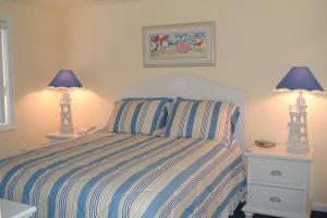 een slaapkamer met een bed met gestreepte lakens en 2 lampen bij Ocean Break in Ocean City
