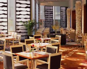 un comedor con mesas y sillas en un restaurante en Beijing New Century Hotel, en Beijing