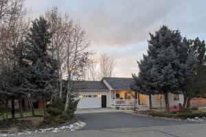 a house with a white garage and two trees at Among the Aspens Family Cottage in Bozeman
