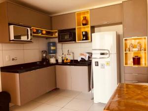 a kitchen with a white refrigerator and a microwave at Iloa Apartamento Lindo in Barra de São Miguel