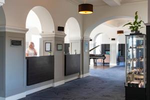 une femme debout au comptoir dans une pièce avec des arches dans l'établissement The Portpatrick Hotel by Compass Hospitality, à Portpatrick