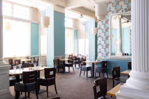 ウェイマスにあるThe Royal Hotel Weymouthの青い壁の部屋にテーブルと椅子が備わるレストラン