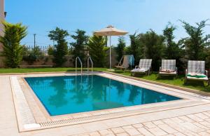 una piscina con 2 sillas y una sombrilla en Villa Harmony-Crete Residences, en Adelianos Kampos