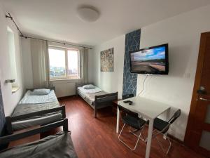 Habitación pequeña con cama, mesa y TV. en Pokoje PANORAMA CITY VIEW- Centrum, en Varsovia