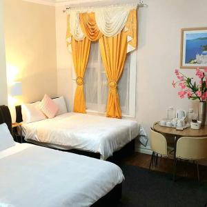 a room with two beds and a table and a window at Gabriel Guesthouse in Rhyl