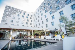 a hotel with a swimming pool in front of a building at ONOMO Hotel Kampala in Kampala