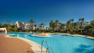 a large swimming pool with palm trees and houses at Life Apartments Costa Ballena in Costa Ballena