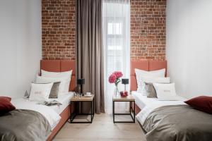 two beds in a room with a brick wall at Hotel Jazz Market Square Wroclaw in Wrocław