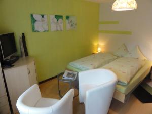 a small bedroom with a bed and a chair at Hotel Primavera in Saas-Grund