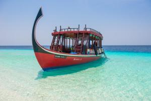 a red boat sitting in the water on the beach at Shamar Guesthouse & Dive in Maamigili