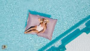 Eine Frau, die auf einem Kissen im Pool liegt. in der Unterkunft Lotus Bungalows in Candidasa