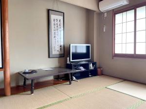 sala de estar con mesa y TV en Business Ryokan Wakakusa en Tsu