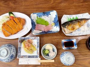 una mesa de madera con platos de comida. en Business Ryokan Wakakusa en Tsu