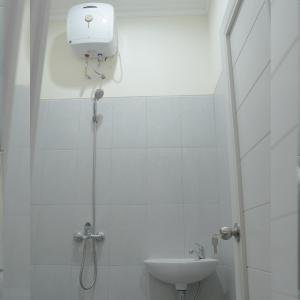 a white bathroom with a shower and a sink at Djuragan Kamar Kayon in Yogyakarta