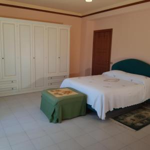 1 dormitorio con cama blanca y reposapiés verde en Stylish Apt TERINA - Le Lincelle, Lamezia - bright, spacious, elegant and with terrace en SantʼEufemia Lamezia