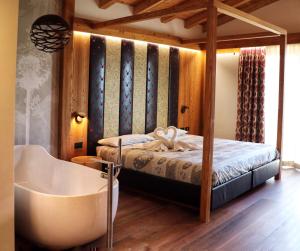 1 dormitorio con cama, bañera y bañera en Hotel Panorama Wellness & Resort en Malosco