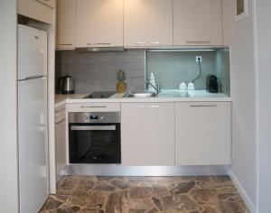una cucina con armadi bianchi, lavandino e frigorifero di Heraklion Old Port Apartments a Heraklion