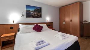 una camera da letto con un grande letto bianco con asciugamani di Residence Pizzo Scalino a Chiesa in Valmalenco
