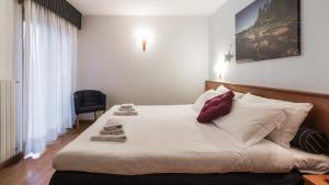 una camera da letto con un letto con lenzuola bianche e cuscini rossi di Residence Pizzo Scalino a Chiesa in Valmalenco