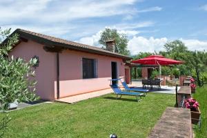 une maison avec une cour dotée d'une chaise et d'un parasol dans l'établissement Caise, à Castelnuovo Magra