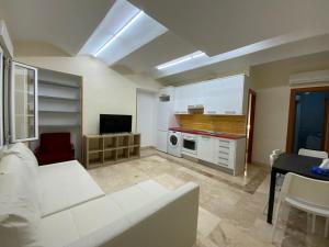 a living room with a white couch and a kitchen at El Jardin del Angel Olmo in Madrid