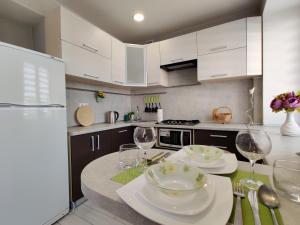 uma cozinha com armários brancos e uma mesa com copos de vinho em Apartament on Oktyabrskaya 132 em Bobruisk