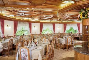 un comedor con mesas y sillas blancas en Hotel Panorama Wellness & Resort en Malosco
