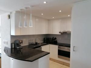 a kitchen with white cabinets and a black counter top at 803 Bermudas - by Stay in Umhlanga in Durban