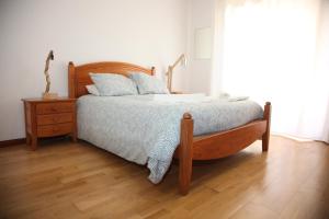 1 dormitorio con cama de madera y suelo de madera en WHAT a fish en Praia da Vagueira