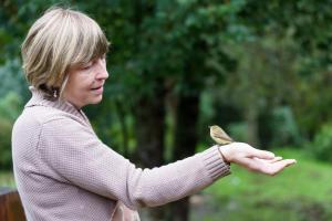 een vrouw die een kleine vogel op haar hand houdt bij Ardenne essentielle in Daverdisse
