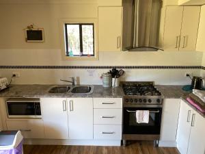 a kitchen with white cabinets and a sink and a stove at The Chalet in Kew