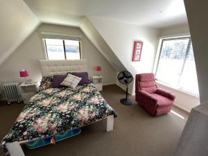 a bedroom with a bed and a pink chair at The Chalet in Kew